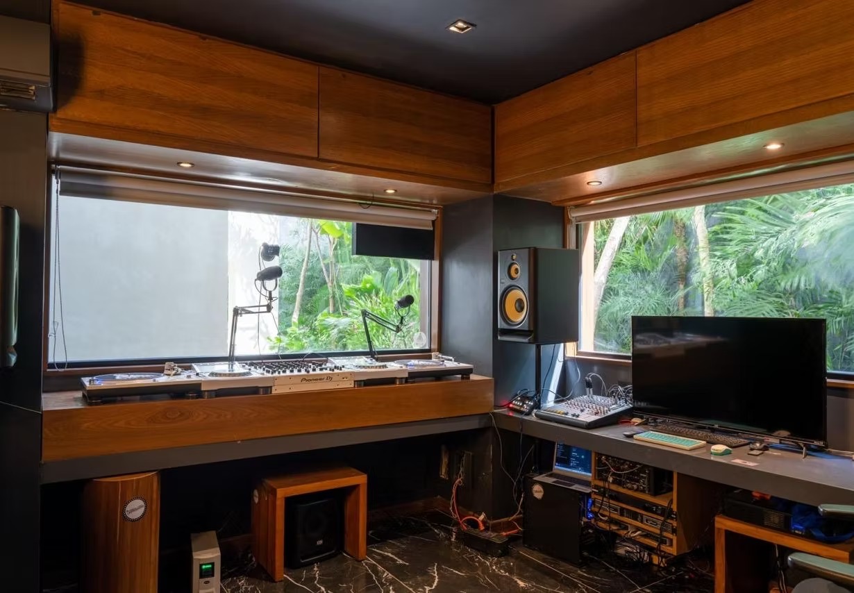 Inside the Downtown Tulum Radio studio, with DJ decks, microphones and windows overlooking tropical greenery